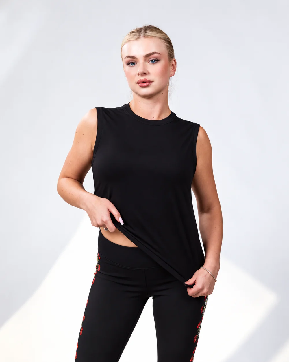 Model wearing the Noir Layer Tank over embroidered leggings